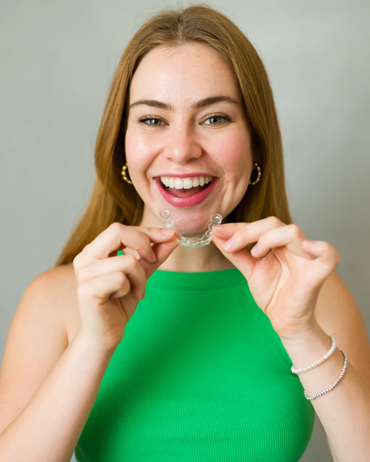 A smiling woman in a green top holding a clear tray